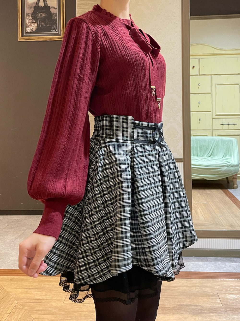 レッド系のニット/セーター、ブラック系のその他アウター、ブラック系のブーツを着用したレディースの秋コーディネートの7枚目の写真