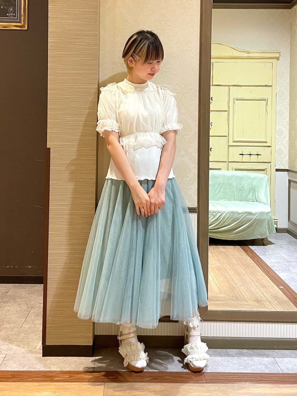 ホワイト系のタンクトップ、ホワイト系のサンダル、グリーン系のスカートを着用したレディースの夏コーディネートの6枚目の写真