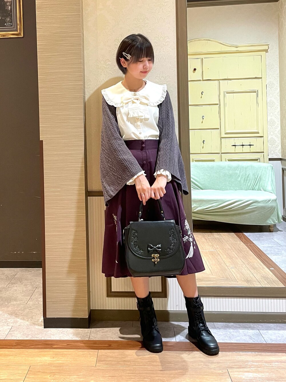 レッド系のスカート、ブラック系のブーツ、ブラック系のショルダーバッグを着用したレディースの秋コーディネートの2枚目の写真