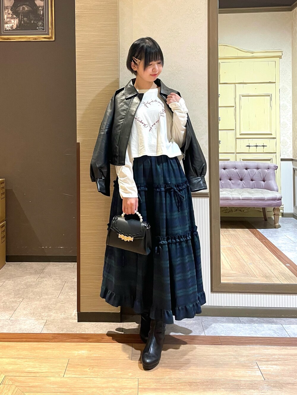 ブラック系のショルダーバッグ、ブラック系のブーツ、グリーン系のスカートを着用したレディースの秋コーディネートの2枚目の写真