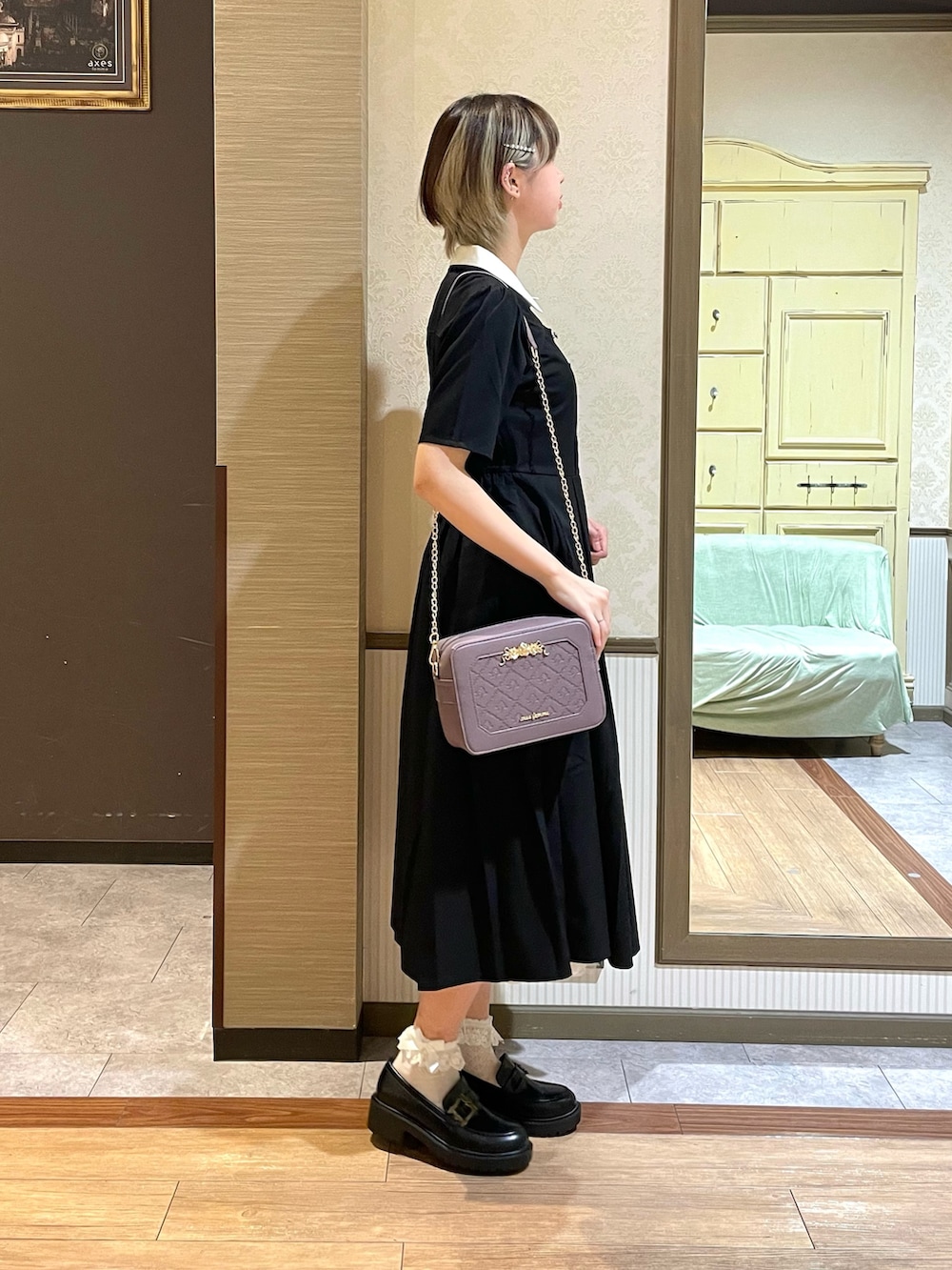 パープル系のショルダーバッグ、ブラック系のワンピース、ホワイト系のタンクトップを着用したレディースの夏コーディネートの3枚目の写真
