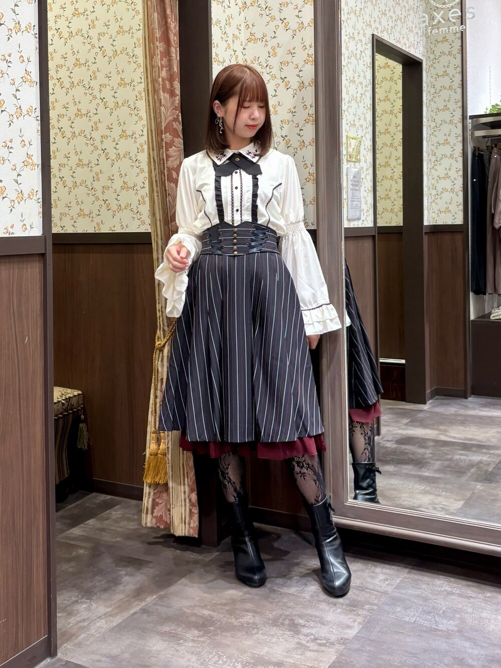 ブルー系のスカート、ブラック系のベスト、ホワイト系のシャツ/ブラウスを着用したレディースの秋コーディネートの2枚目の写真