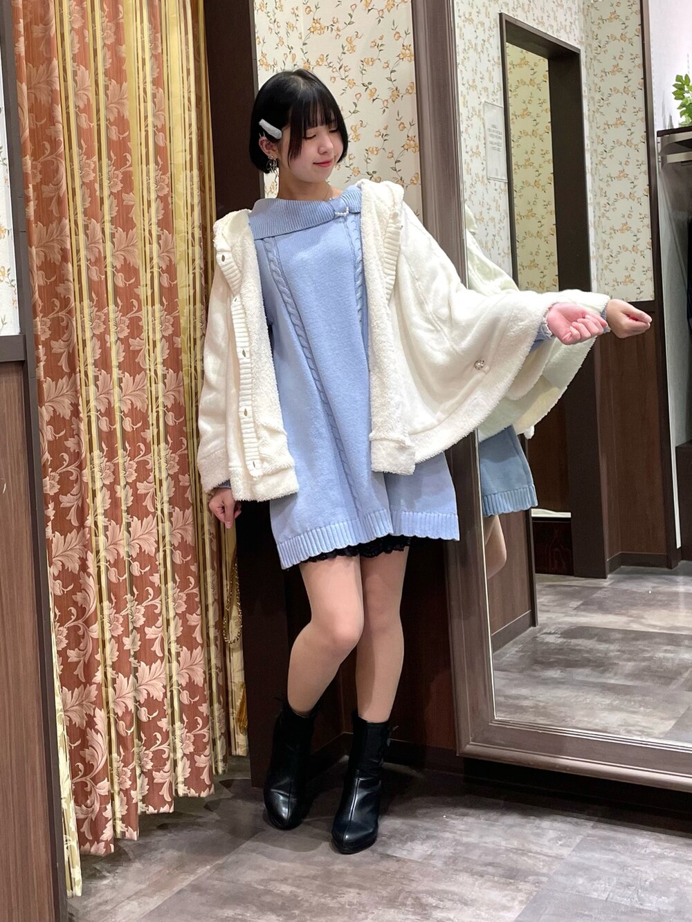 ブルー系のチュニック、ホワイト系のポンチョ、ホワイト系のショルダーバッグを着用したレディースの冬コーディネートの5枚目の写真