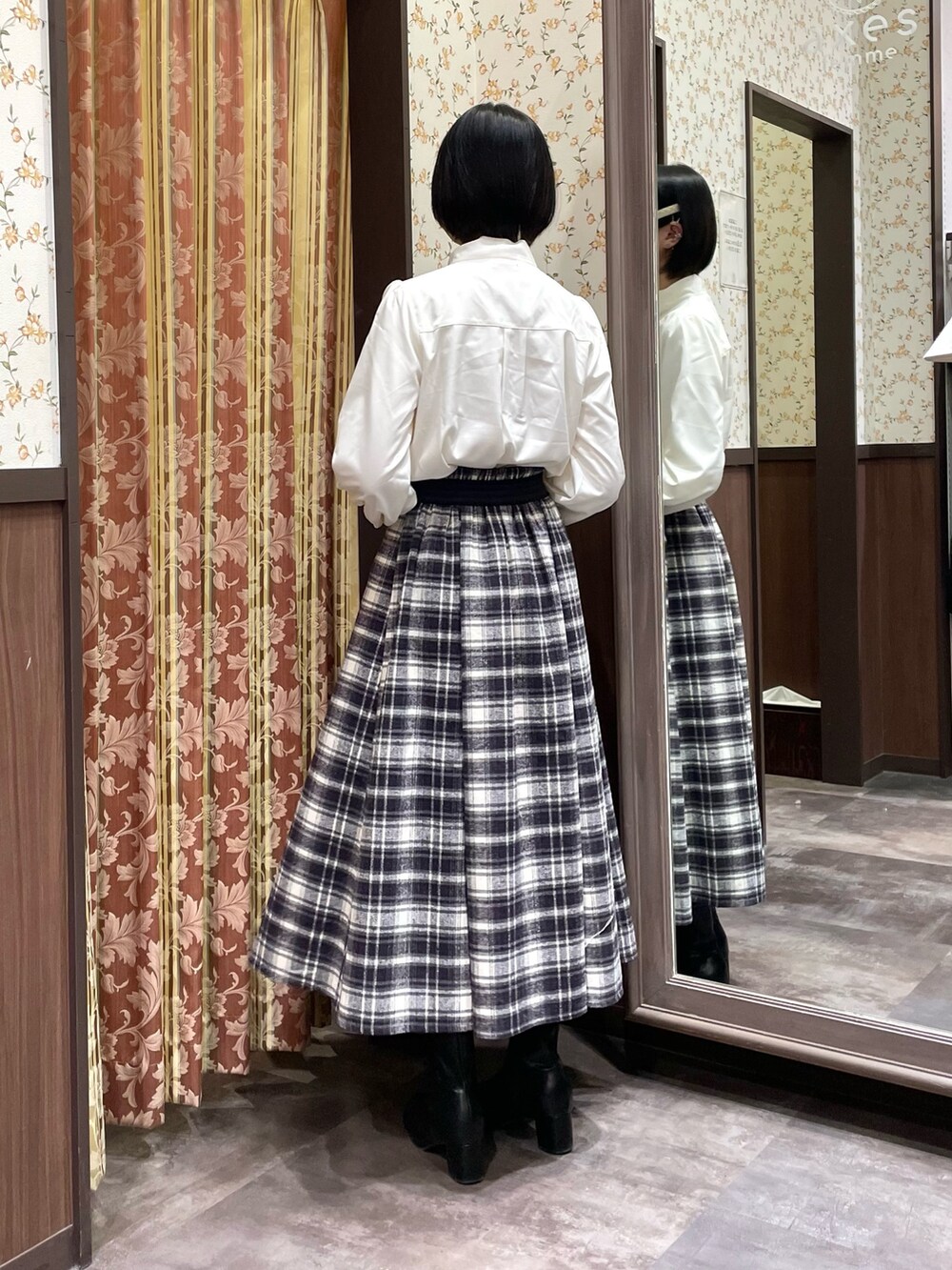 パープル系のスカート、ホワイト系のシャツ/ブラウス、ブラック系のブーツを着用したレディースの冬コーディネートの2枚目の写真