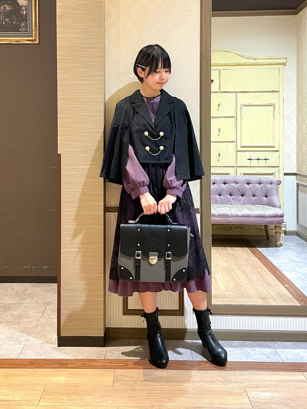 ブラック系のテーラードジャケット、パープル系のワンピース、ブラック系のブーツを着用したレディースの秋コーディネートの2枚目の写真