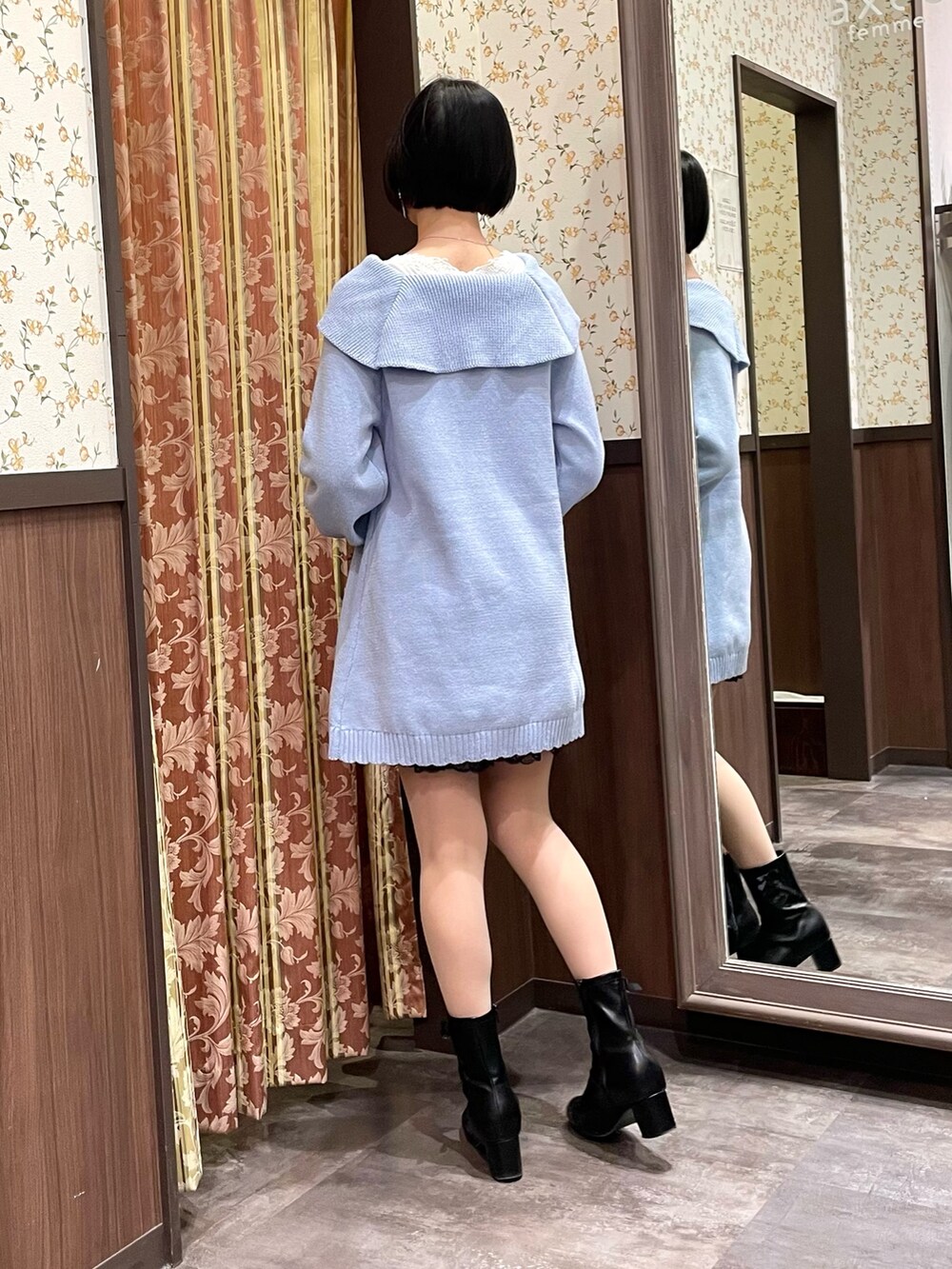 ブルー系のチュニック、ホワイト系のポンチョ、ホワイト系のショルダーバッグを着用したレディースの冬コーディネートの3枚目の写真