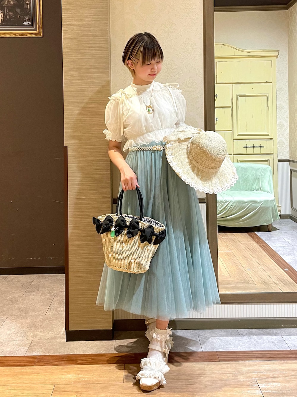 ホワイト系のタンクトップ、ホワイト系のサンダル、グリーン系のスカートを着用したレディースの夏コーディネートの3枚目の写真