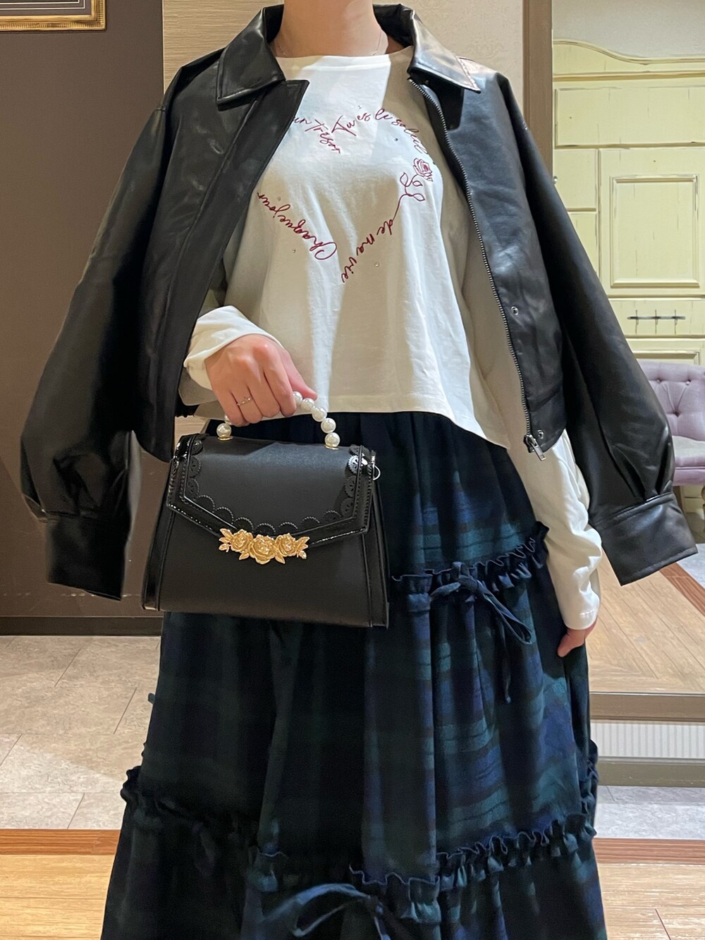 ブラック系のショルダーバッグ、ブラック系のブーツ、グリーン系のスカートを着用したレディースの秋コーディネートの3枚目の写真