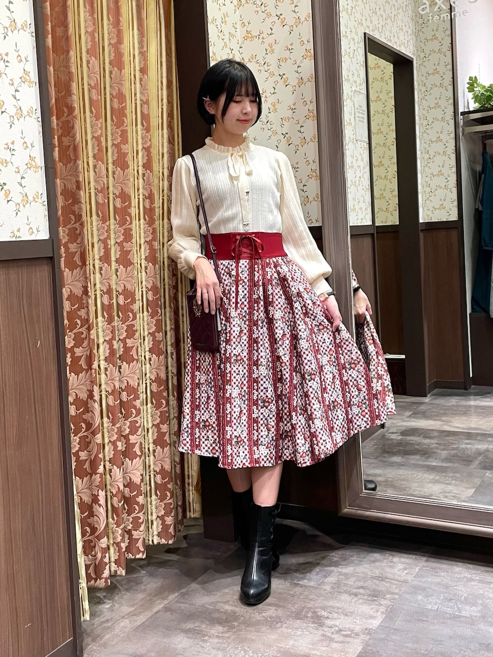 レッド系のスカート、ホワイト系のニット/セーター、ブラウン系のダッフルコートを着用したレディースの冬コーディネートの2枚目の写真