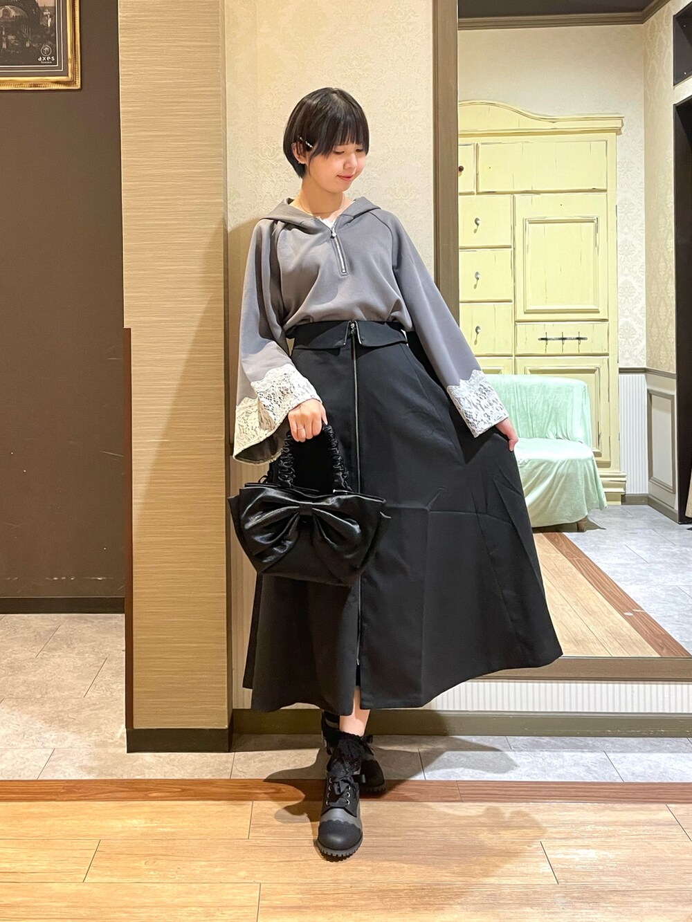 ブラック系のブーツ、ブラック系のトートバッグ、ホワイト系のタンクトップを着用したレディースの夏コーディネートの2枚目の写真