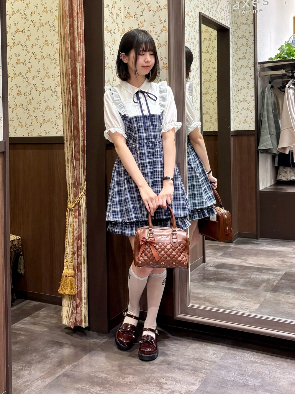 ブラウン系のボストンバッグ、ブルー系のセットアップ、ブラウン系のローファーを着用したレディースの夏コーディネートの3枚目の写真