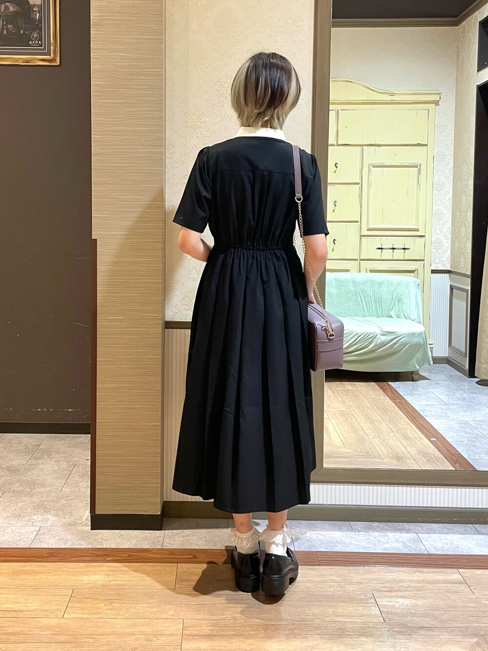 パープル系のショルダーバッグ、ブラック系のワンピース、ホワイト系のタンクトップを着用したレディースの夏コーディネートの4枚目の写真