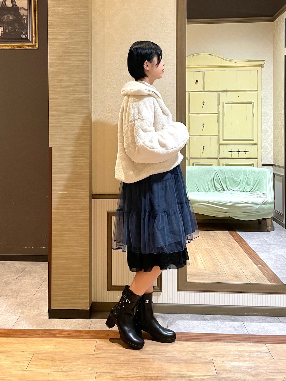 ホワイト系のピーコート、ブルー系のワンピース、ブラック系のブーツを着用したレディースの秋コーディネートの3枚目の写真