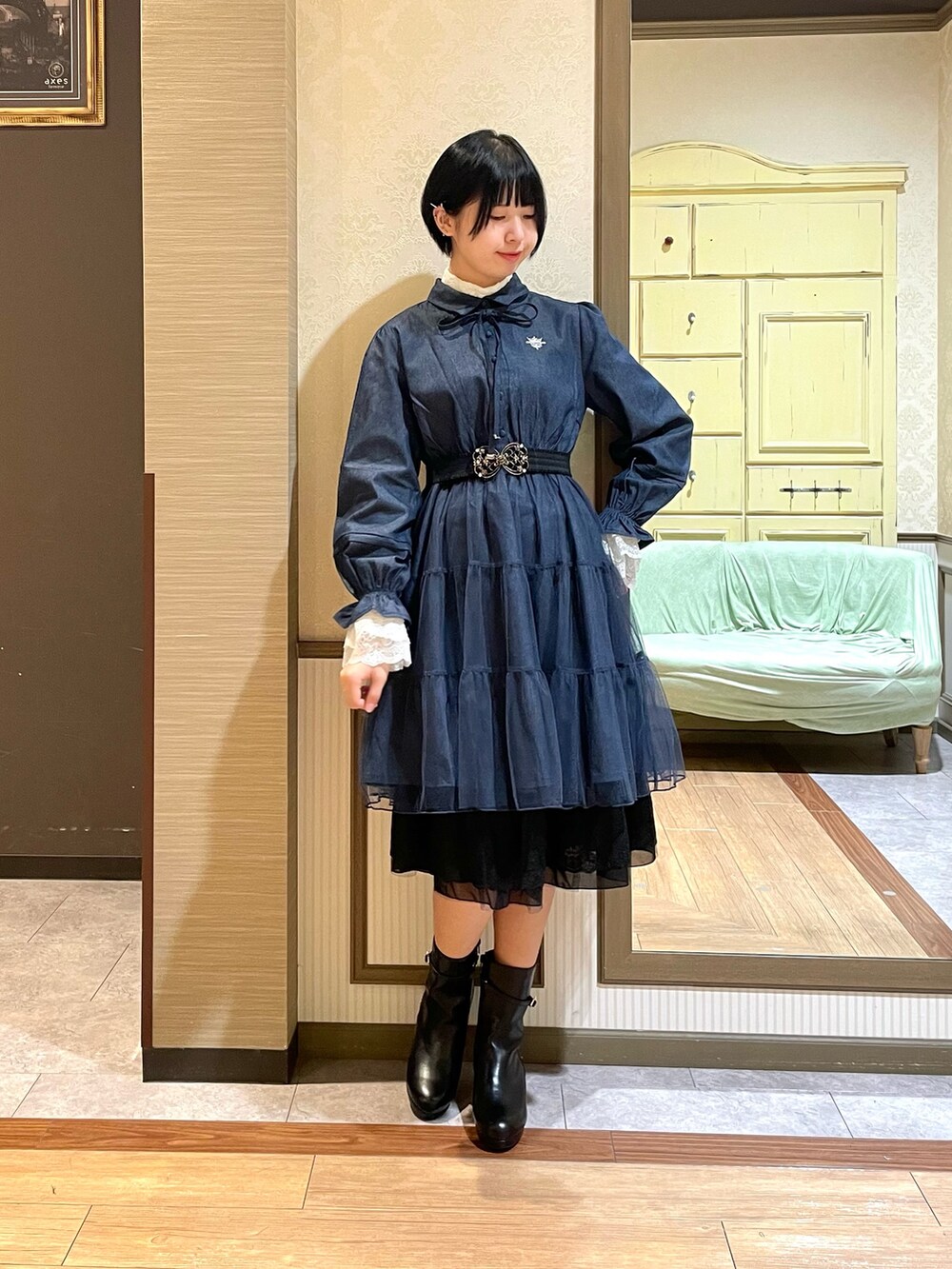 ホワイト系のピーコート、ブルー系のワンピース、ブラック系のブーツを着用したレディースの秋コーディネートの6枚目の写真