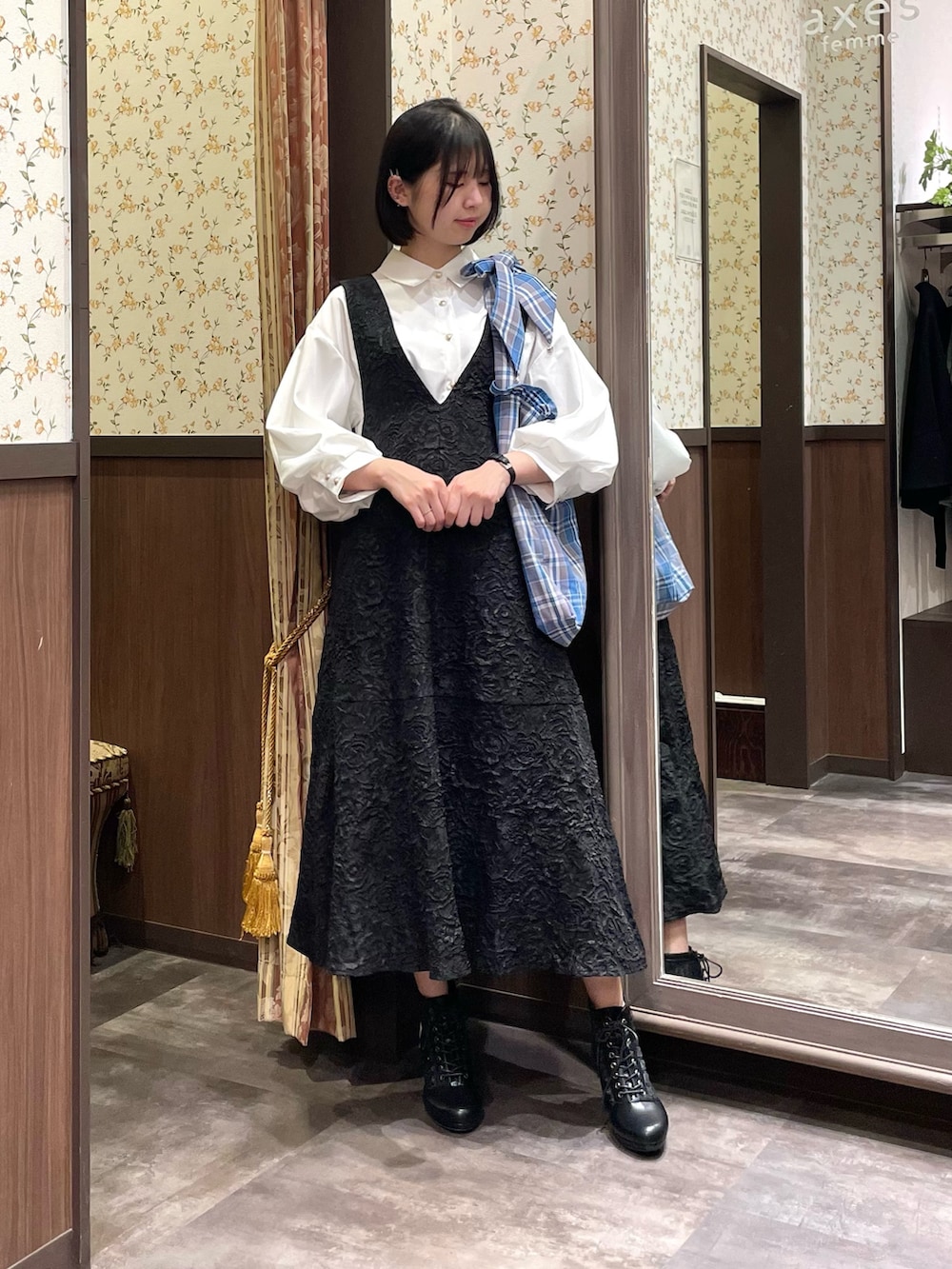 ホワイト系のシャツ/ブラウス、ブラック系のジャンパースカート、ブラック系のブーツを着用したレディースの春コーディネートの4枚目の写真