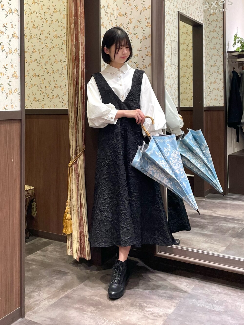 ホワイト系のシャツ/ブラウス、ブラック系のジャンパースカート、ブラック系のブーツを着用したレディースの春コーディネートの6枚目の写真