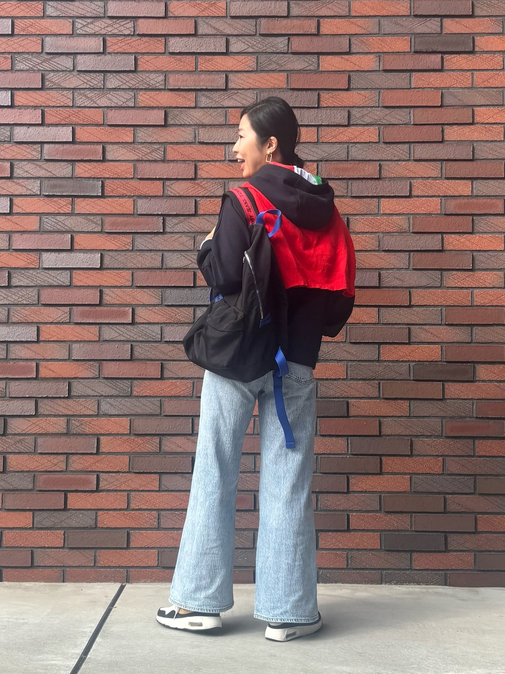 ブラック系のパーカー、ブルー系のデニムパンツ、ブラック系のバックパック/リュックを着用したレディースの秋コーディネートの2枚目の写真