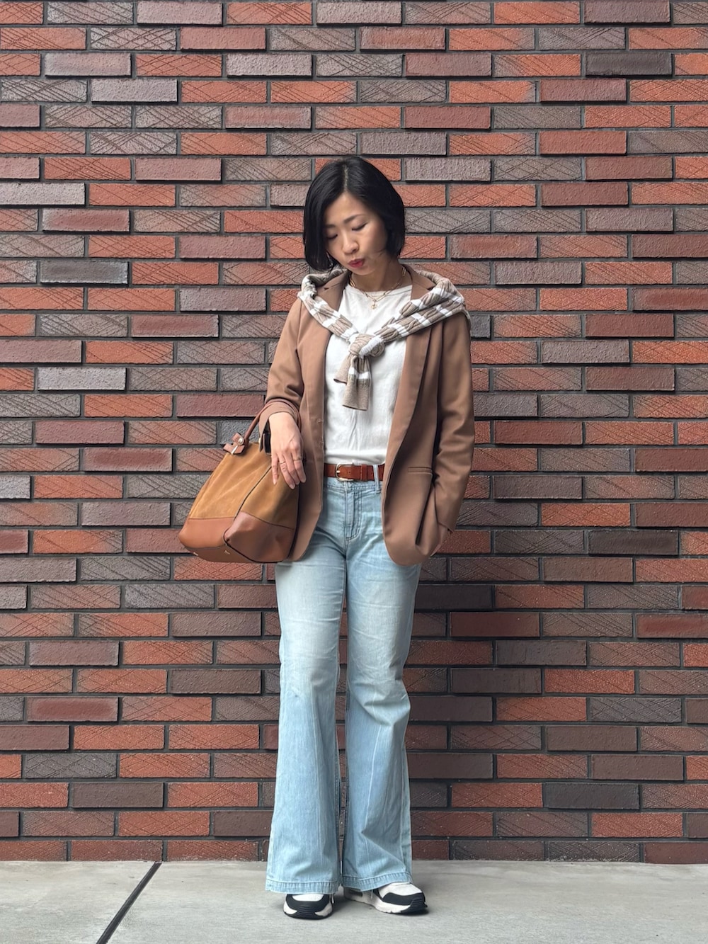 ブラウン系のトートバッグ、ブルー系のデニムパンツ、ホワイト系のトップスを着用したレディースの冬コーディネートの2枚目の写真