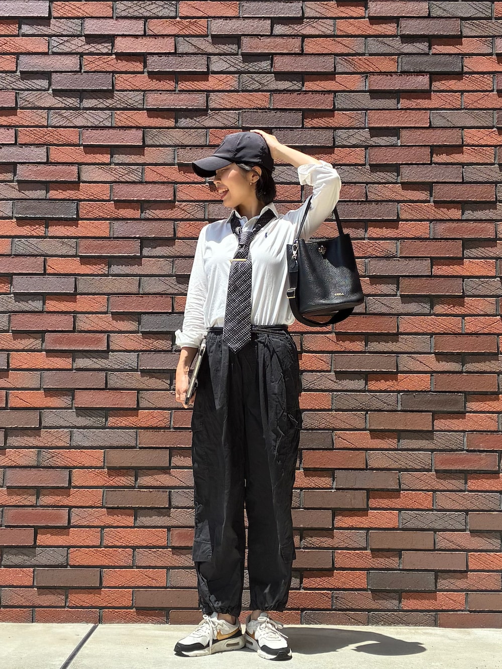 ブラック系のカーゴパンツ、ブラック系のスニーカー、ホワイト系のシャツ/ブラウスを着用したレディースの春コーディネートの2枚目の写真