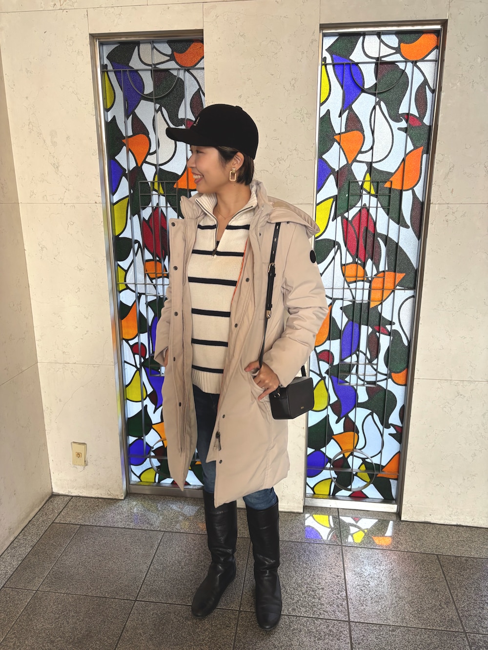 ホワイト系のニット/セーター、ベージュ系のダウンジャケット/コート、ブラック系のショルダーバッグを着用したレディースの冬コーディネートの2枚目の写真