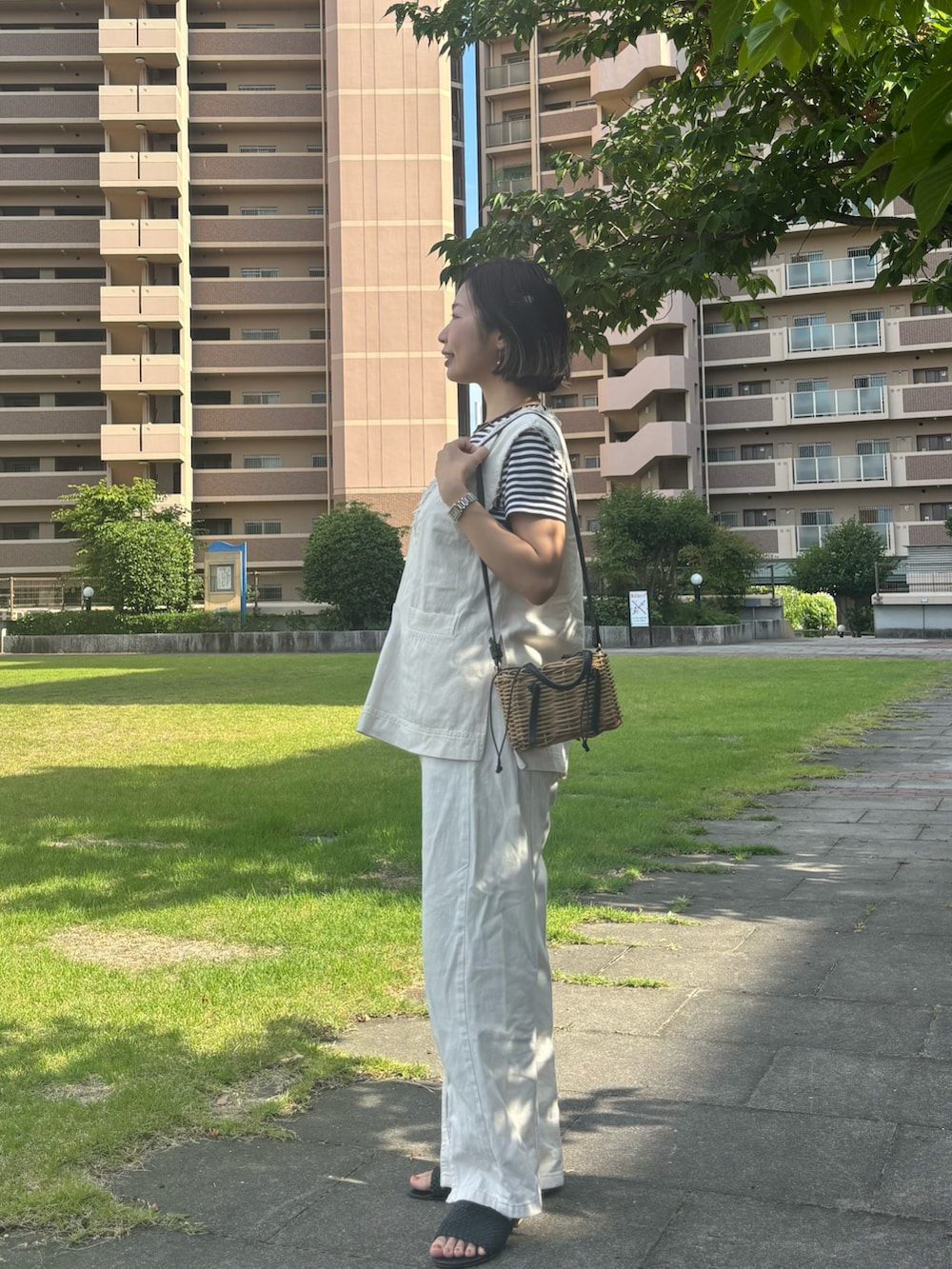 ホワイト系のベスト、ブラック系のTシャツ/カットソー、ホワイト系のデニムパンツを着用したレディースの夏コーディネートの3枚目の写真