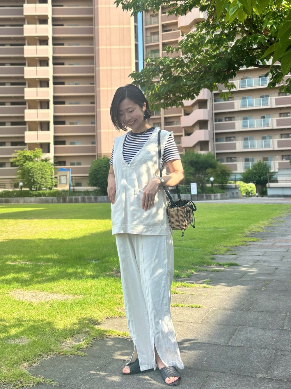 ホワイト系のベスト、ブラック系のTシャツ/カットソー、ホワイト系のデニムパンツを着用したレディースの夏コーディネートの2枚目の写真