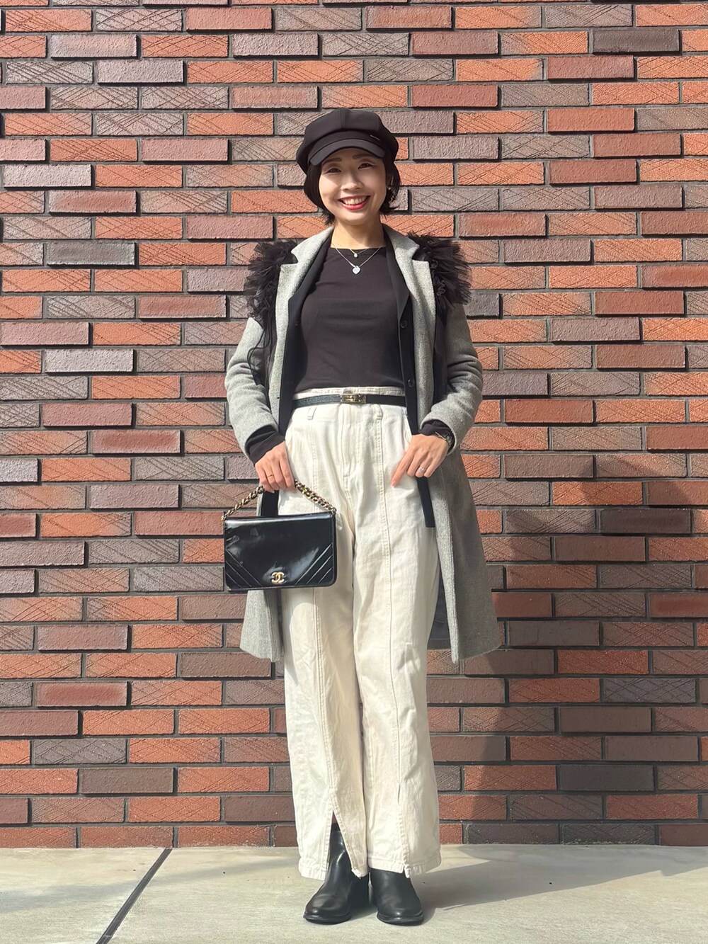 ブラック系のTシャツ/カットソー、ブラック系のベスト、グレー系のチェスターコートを着用したレディースの冬コーディネートの2枚目の写真