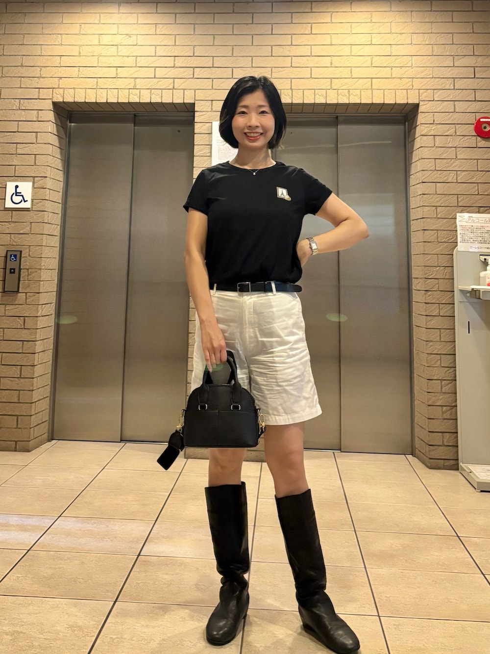 ブラック系のTシャツ/カットソー、ホワイト系のパンツ、ブラック系のボストンバッグを着用したレディースの夏コーディネートの2枚目の写真