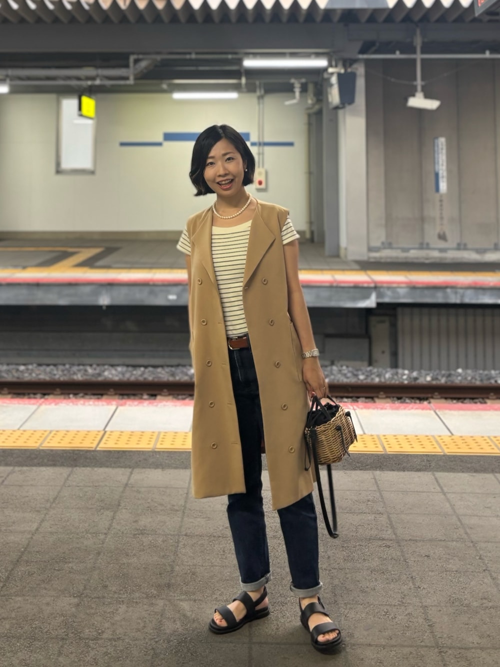 ブラック系のサンダル、ホワイト系のTシャツ/カットソー、ベージュ系のベストを着用したレディースの夏コーディネートの2枚目の写真