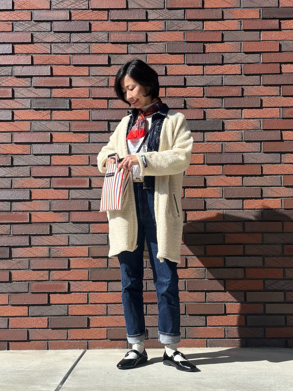 ブラック系のパンプス、ホワイト系のキャミソール、ブルー系のデニムジャケットを着用したレディースの冬コーディネートの2枚目の写真