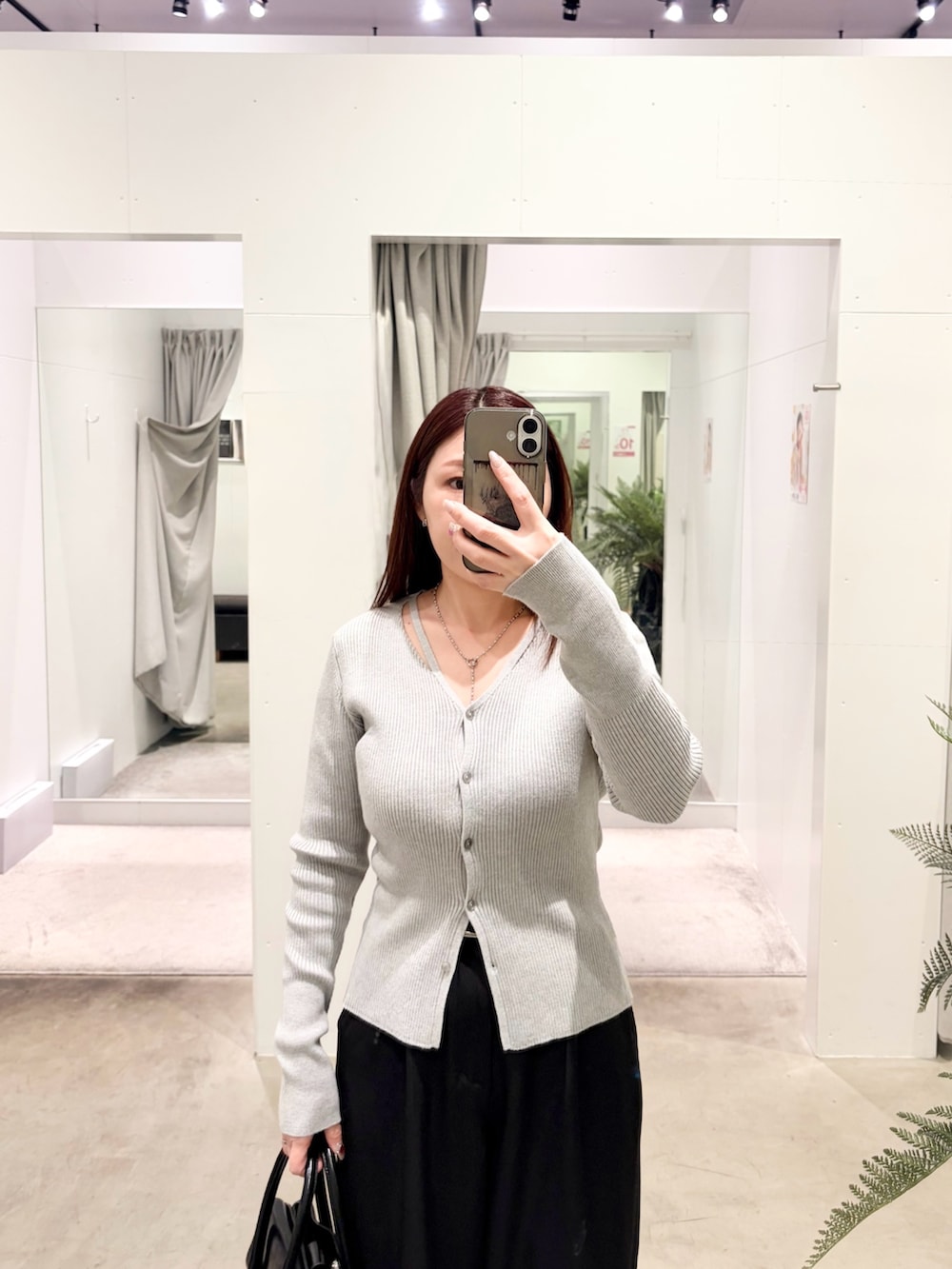 ブラック系のスラックス、グレー系のカーディガン/ボレロ、ブラック系のハンドバッグを着用したレディースの冬コーディネートの2枚目の写真