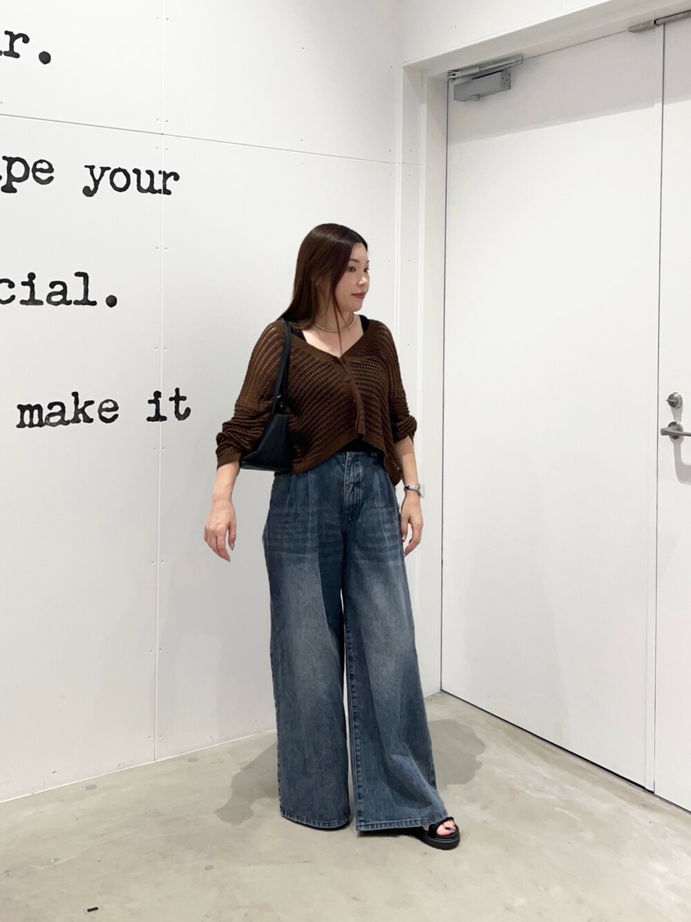 ブルー系のデニムパンツ、ブラック系のショルダーバッグ、ブラウン系のカーディガン/ボレロを着用したレディースの夏コーディネートの3枚目の写真