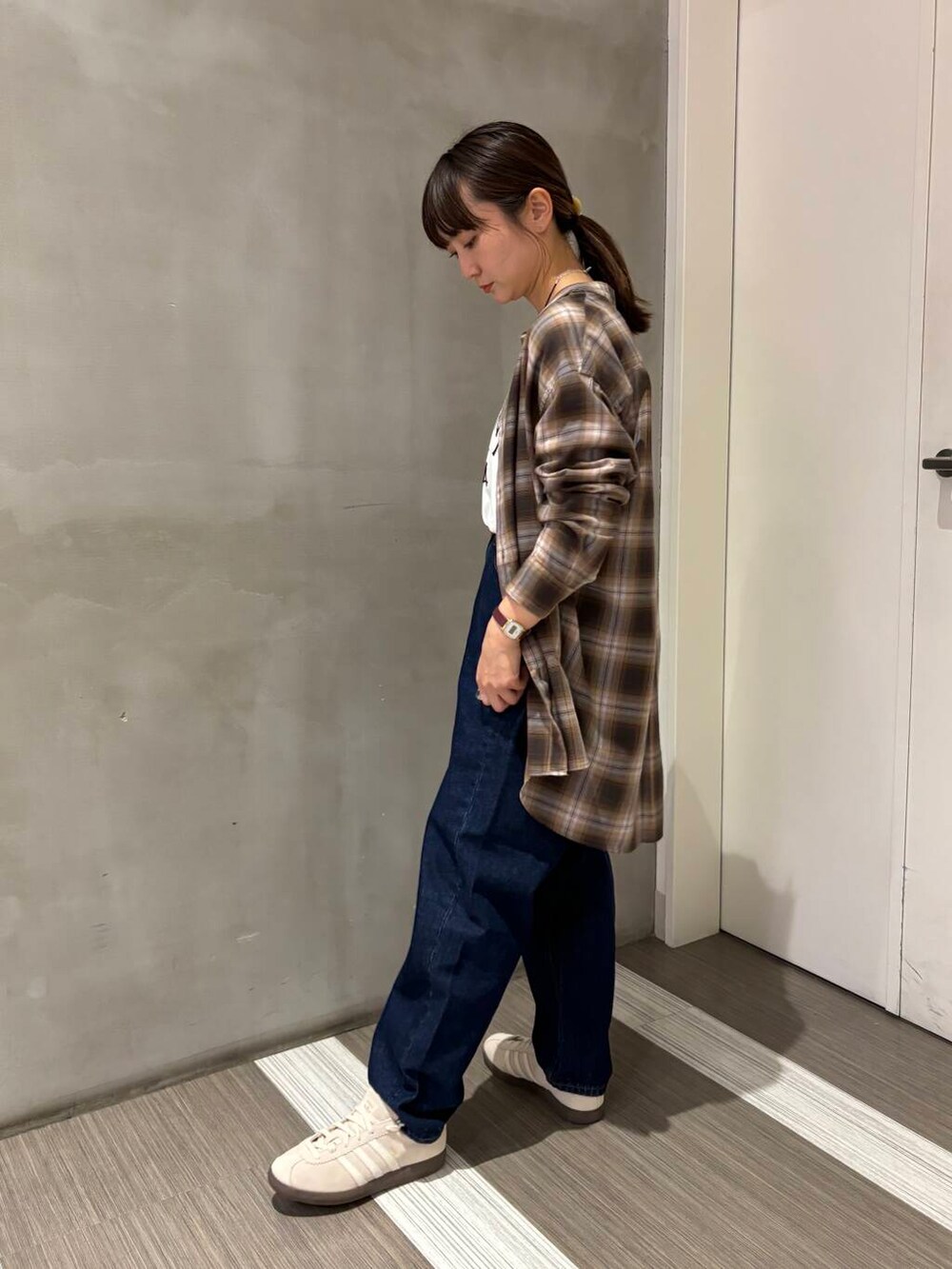 ブルー系のデニムパンツ、ブラウン系のシャツ/ブラウス、ホワイト系のスニーカーを着用したレディースの秋コーディネートの2枚目の写真