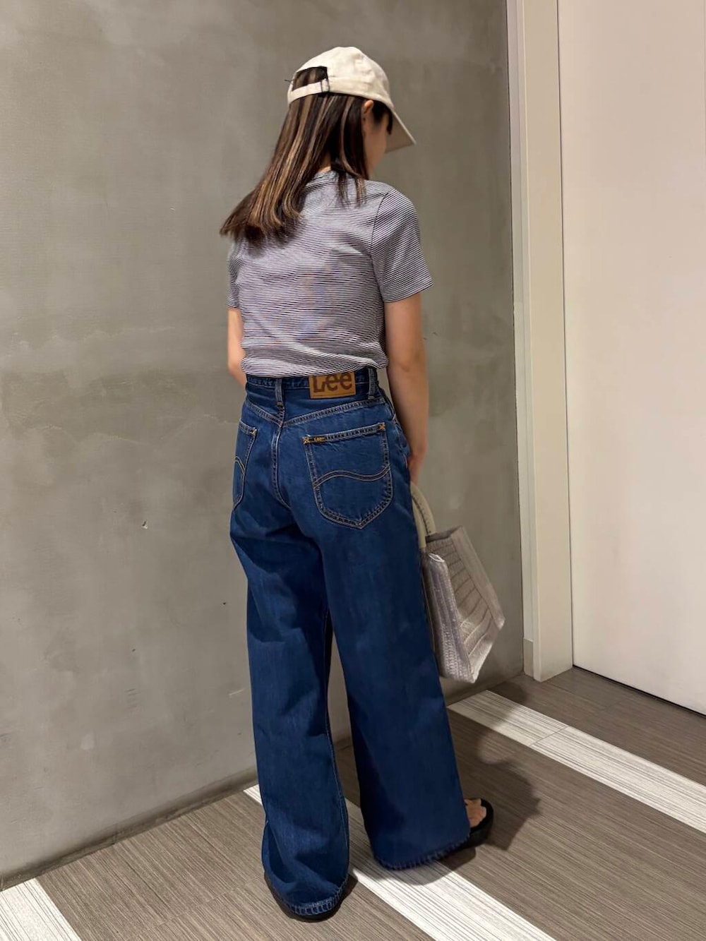 ブルー系のデニムパンツ、ブラック系のサンダル、グレー系のハンドバッグを着用したレディースの春コーディネートの4枚目の写真