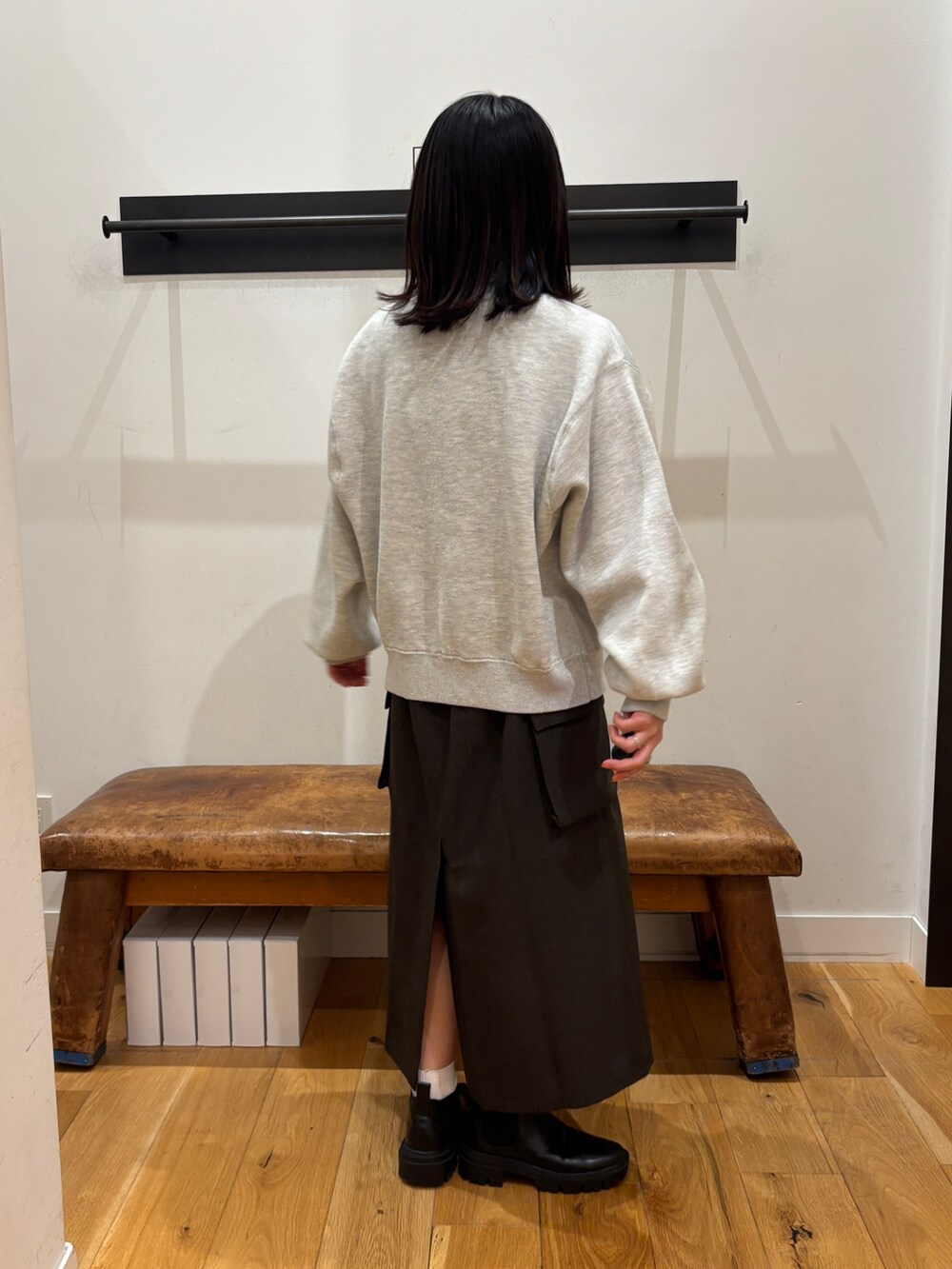 グレー系のニット/セーター、ホワイト系のTシャツ/カットソー、ブラウン系のスカートを着用したレディースの秋コーディネートの3枚目の写真