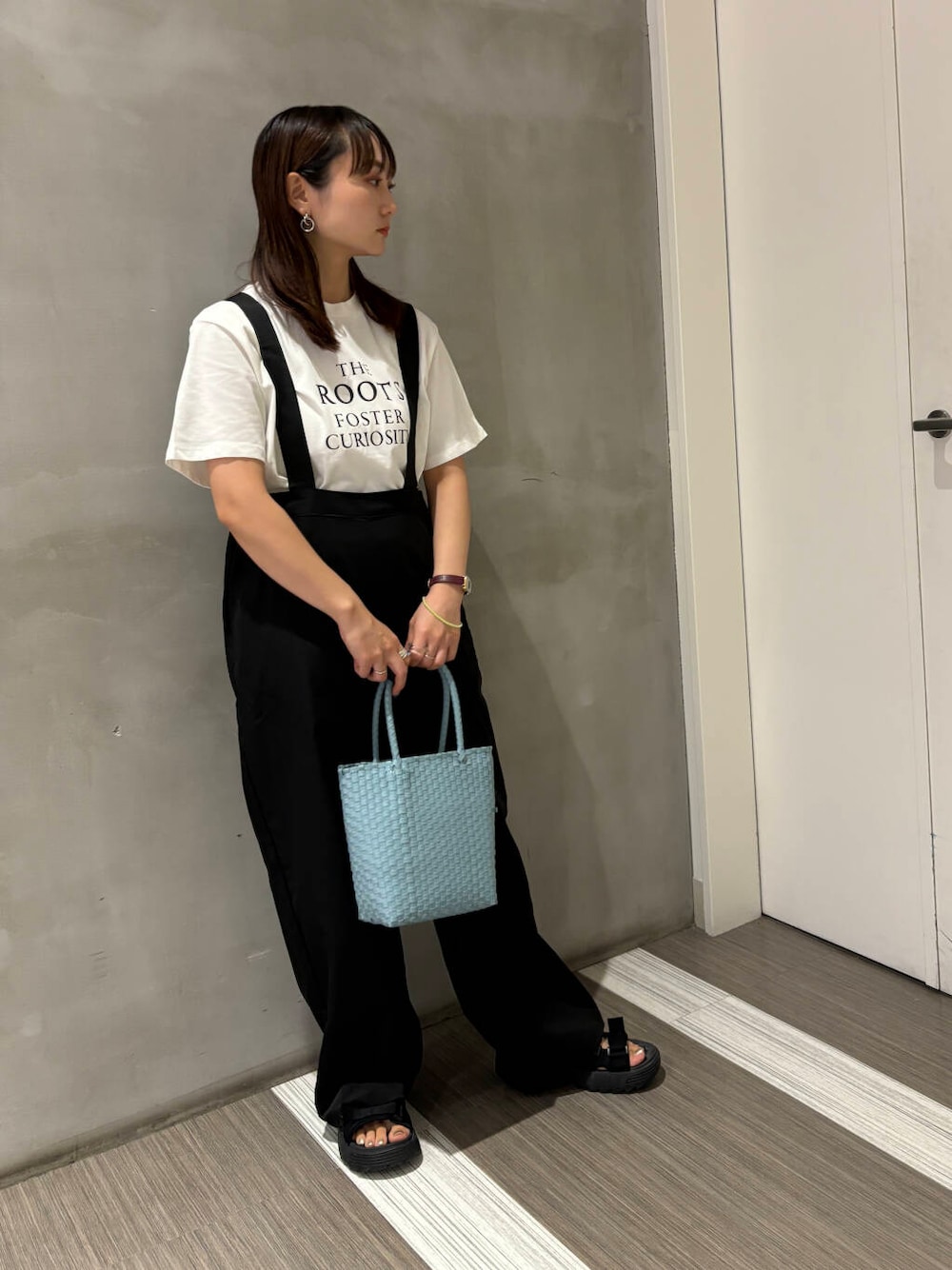 ブルー系のトートバッグ、ブラック系のサロペット/オーバーオール、ホワイト系のTシャツ/カットソーを着用したレディースの夏コーディネートの2枚目の写真