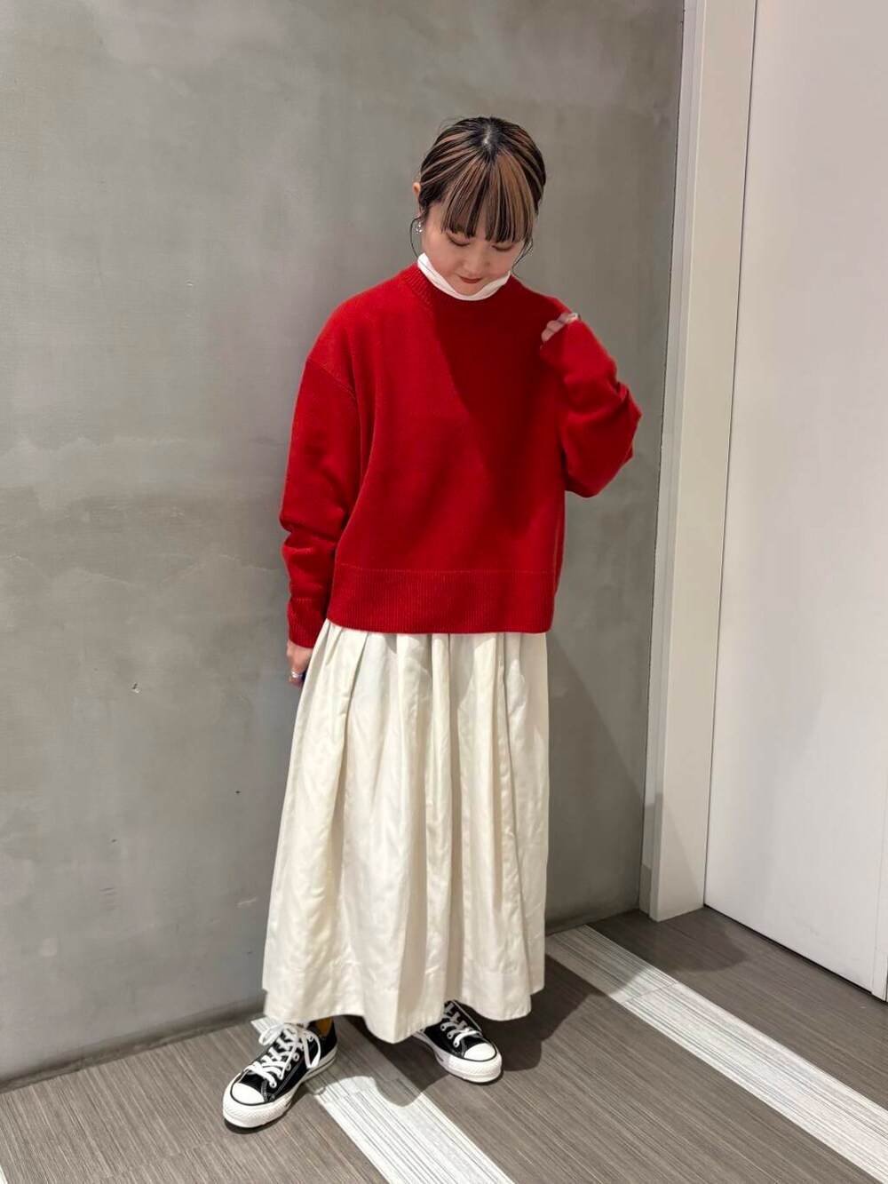 ブラック系のスニーカー、ホワイト系のスカート、レッド系のニット/セーターを着用したレディースの冬コーディネートの2枚目の写真