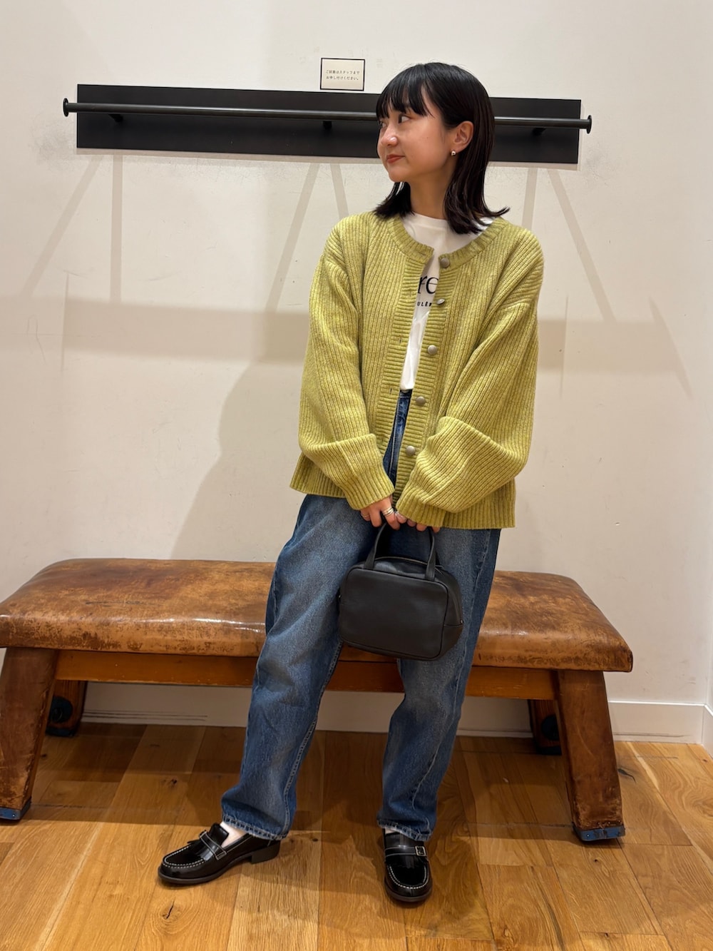 グリーン系のカーディガン/ボレロ、ホワイト系のTシャツ/カットソー、ブラック系のボストンバッグを着用したレディースの秋コーディネートの5枚目の写真