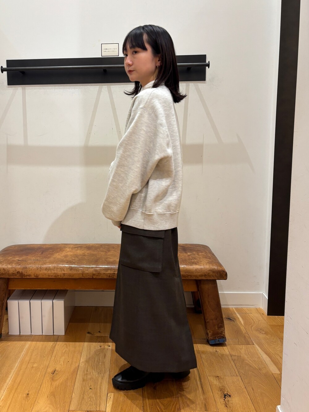 グレー系のニット/セーター、ホワイト系のTシャツ/カットソー、ブラウン系のスカートを着用したレディースの秋コーディネートの4枚目の写真