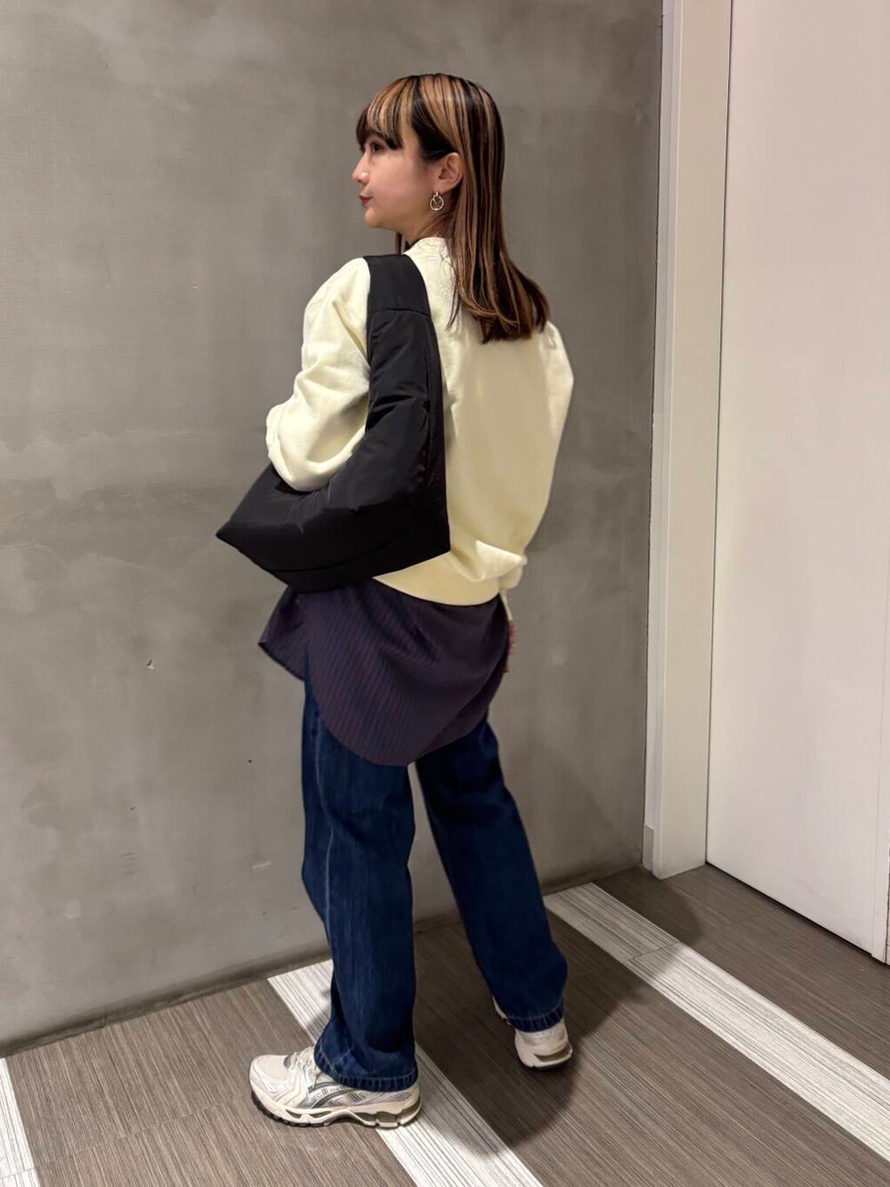 ブルー系のTシャツ/カットソー、ブルー系のデニムパンツ、ブラック系のトートバッグを着用したレディースの冬コーディネートの2枚目の写真