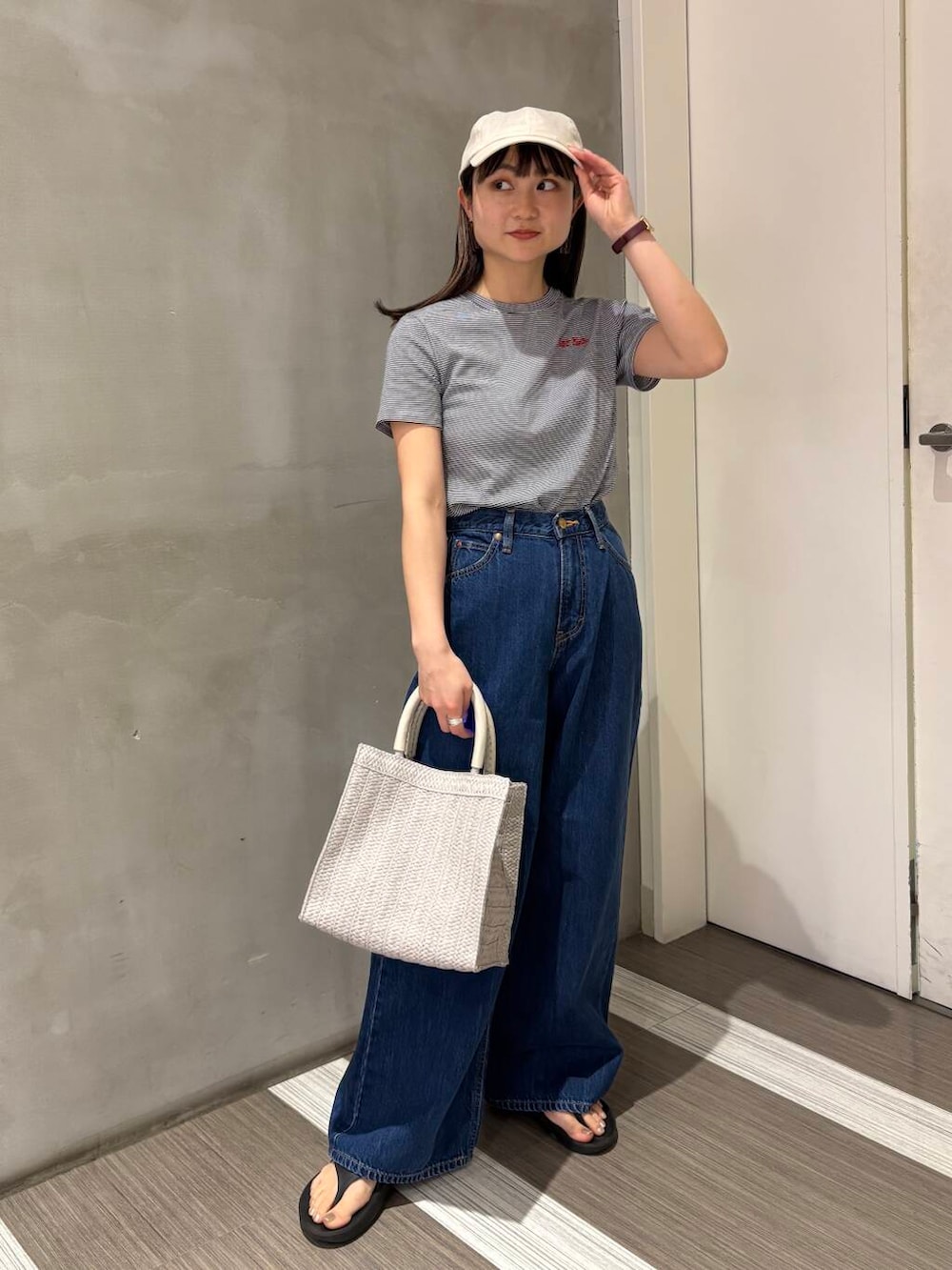 ブルー系のデニムパンツ、ブラック系のサンダル、グレー系のハンドバッグを着用したレディースの春コーディネートの2枚目の写真