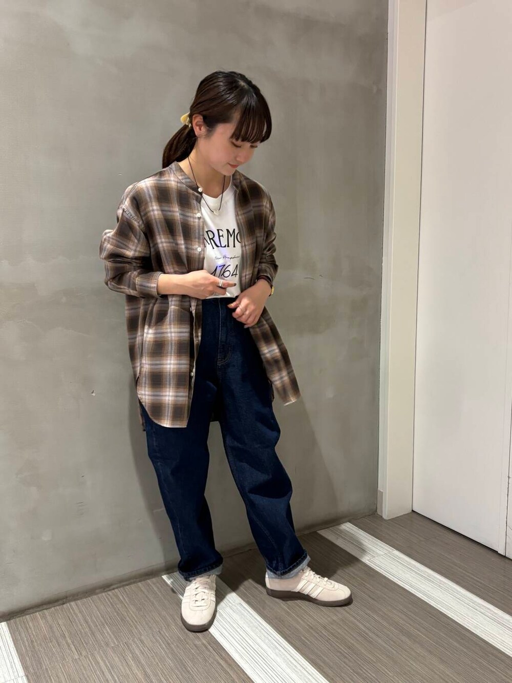 ブルー系のデニムパンツ、ブラウン系のシャツ/ブラウス、ホワイト系のスニーカーを着用したレディースの秋コーディネートの3枚目の写真