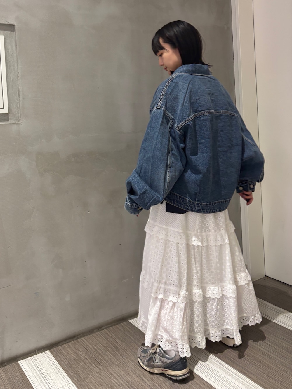 ブルー系のデニムジャケット、グレー系のTシャツ/カットソー、ホワイト系のスカートを着用したレディースの秋コーディネートの4枚目の写真