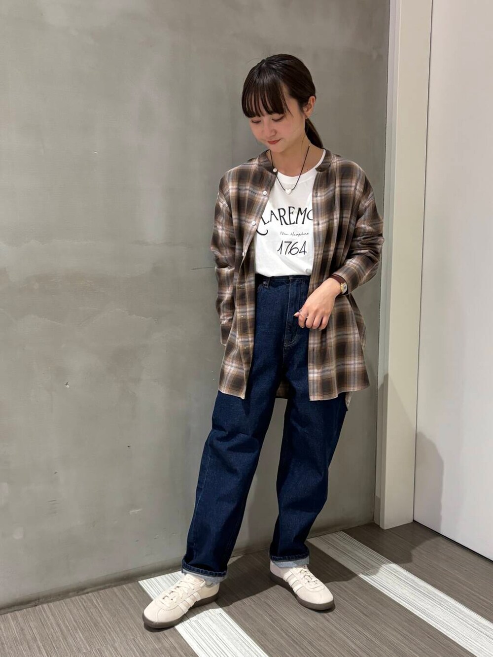 ブルー系のデニムパンツ、ブラウン系のシャツ/ブラウス、ホワイト系のスニーカーを着用したレディースの秋コーディネートの5枚目の写真