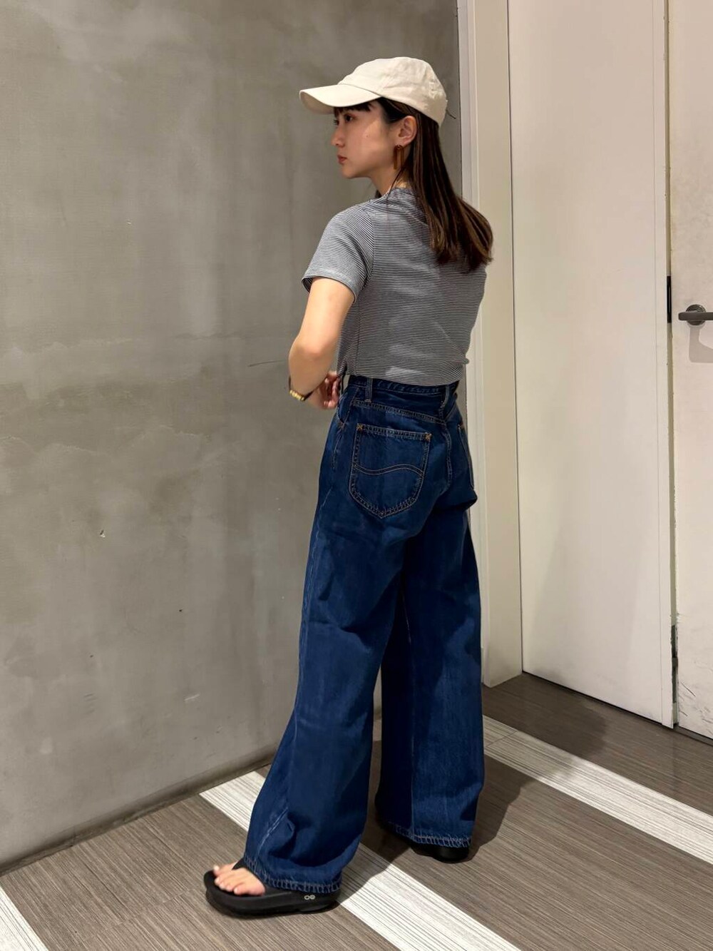 ブルー系のデニムパンツ、ブラック系のサンダル、グレー系のハンドバッグを着用したレディースの春コーディネートの3枚目の写真