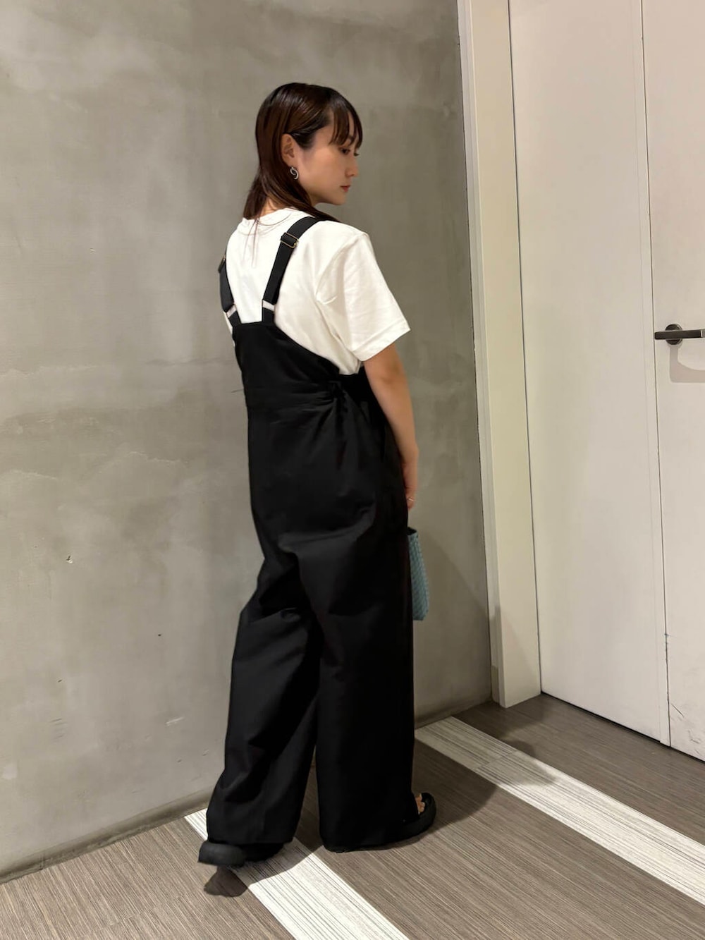ブルー系のトートバッグ、ブラック系のサロペット/オーバーオール、ホワイト系のTシャツ/カットソーを着用したレディースの夏コーディネートの4枚目の写真