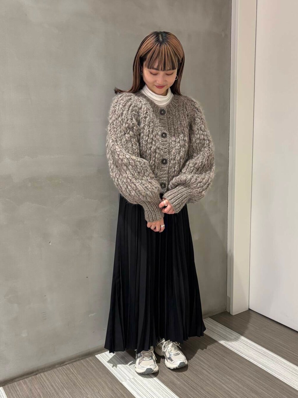 ブラウン系のカーディガン/ボレロ、ブラック系のスカートを着用したレディースの冬コーディネートの2枚目の写真