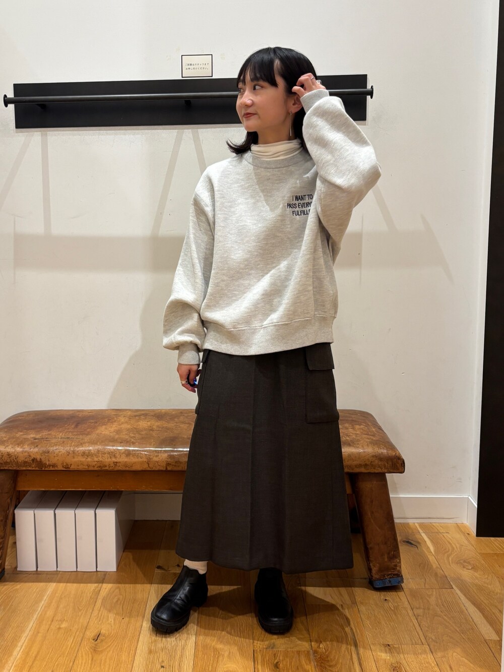 グレー系のニット/セーター、ホワイト系のTシャツ/カットソー、ブラウン系のスカートを着用したレディースの秋コーディネートの2枚目の写真