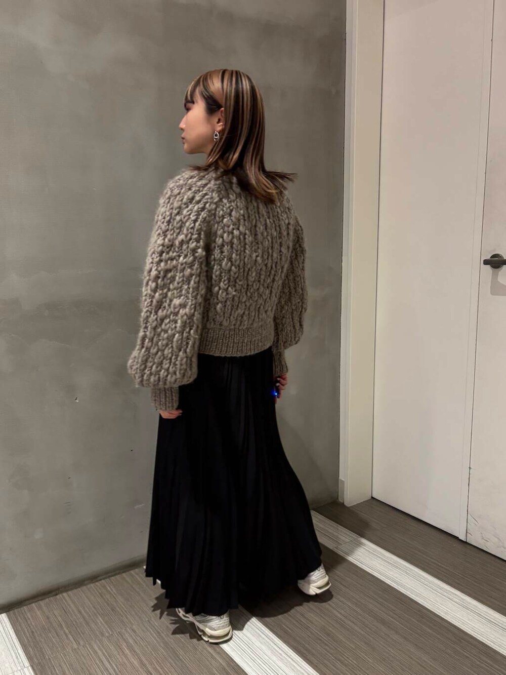 ブラウン系のカーディガン/ボレロ、ブラック系のスカートを着用したレディースの冬コーディネートの4枚目の写真
