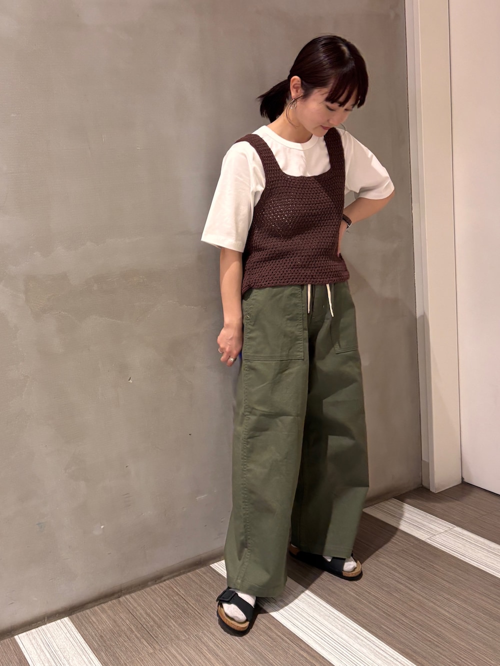 グリーン系のその他パンツ、ブラウン系のタンクトップ、ホワイト系のTシャツ/カットソーを着用したレディースの春コーディネートの2枚目の写真
